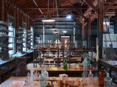 Moderna’s mRNA-5671 Vaccine Stalls After Merck Ends Trial A scientist examines a vial labeled mRNA-5671 in a modern laboratory, symbolizing the stalled cancer vaccine research.