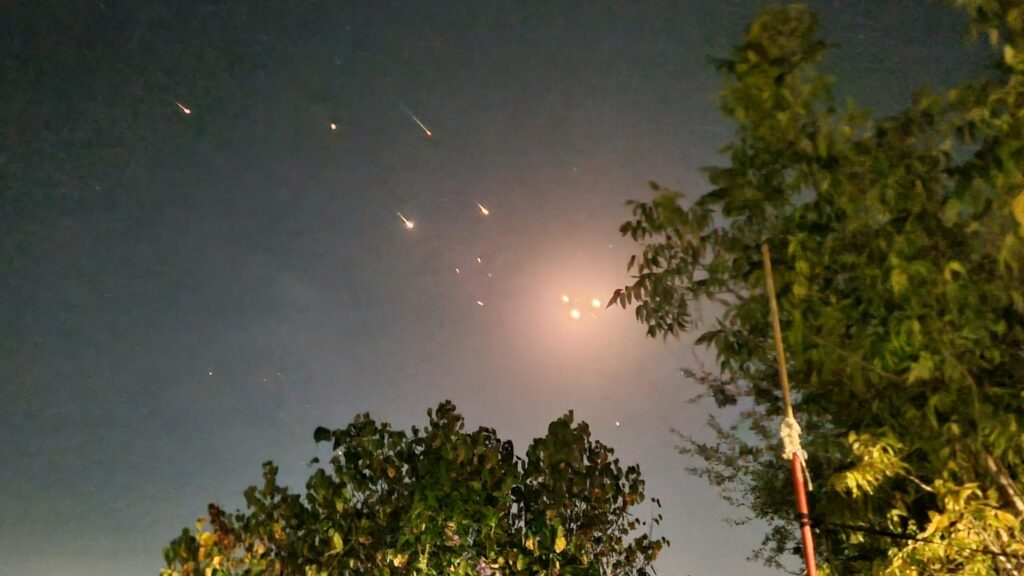 Missiles streak across the sky above a city skyline during an Iran-Israel military confrontation in 2024.