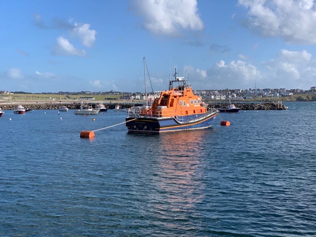 Emergency responders recover a body from the cold waters of the English Channel near a small overcrowded boat.