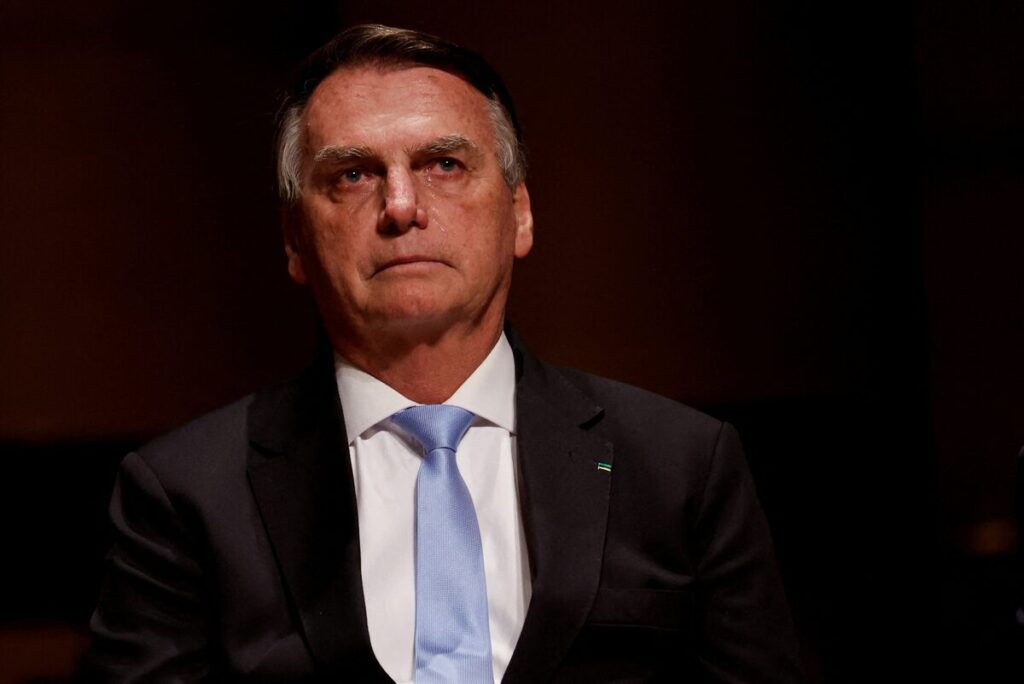 Jair Bolsonaro speaking at a political event in Brazil, gesturing with his hands.